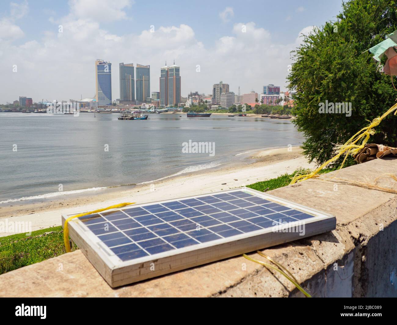 Dar es Salaam, Tansania - Februar 2021: Stadtzentrum mit Wolkenkratzern vom Fährterminal Kigamboni aus gesehen, und einer Solarbatterie auf dem ersten Plan Stockfoto