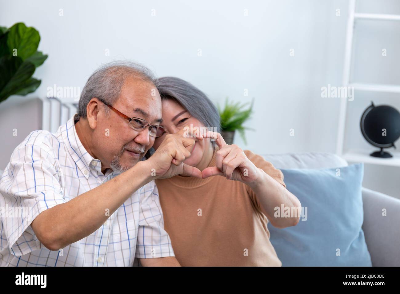 Ein glückliches Rentnerpaar, das sich zu Hause ansieht. Rentner, die sich zu Hause gegenseitig versorgen. Stockfoto