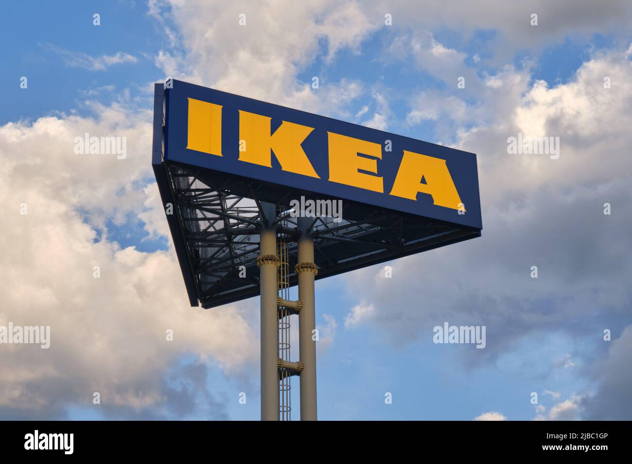 IKEA-Logo auf hohem Stock, mit Abendwolken. IKEA ist ein in Schweden gegründetes multinationales Konglomerat, das fertige Möbel entwirft und verkauft Stockfoto