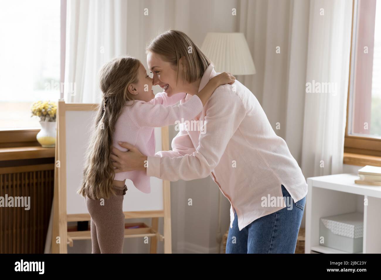 Mutter ihre kleine Tochter berührt Nasen, genießt einen Moment der Zärtlichkeit Stockfoto