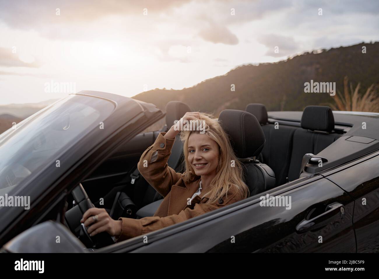 Nahaufnahme des Porträts einer fröhlichen jungen hübschen Frau, die beim Fahren eines Cabrios lächelt Stockfoto
