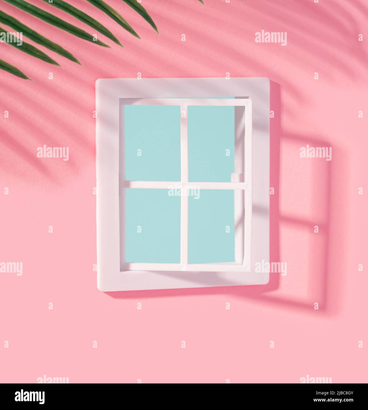 Pastellrosa Fassade mit weißen Fenstern und Palmen, die einen Schatten werfen. Sommerstimmung minimaler Hintergrund. Stockfoto