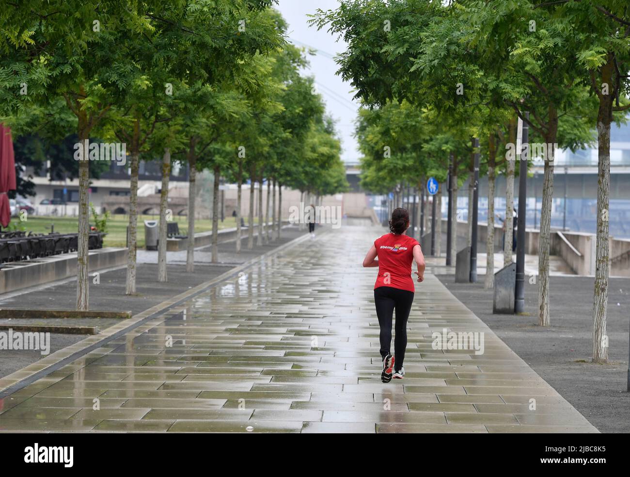 05. Juni 2022, Nordrhein-Westfalen, Köln: Ein Jogger läuft auf der Rheinpromenade durch den Regen. Wo gewöhnlich Massen von Menschen spazieren, gab es am Pfingstsonntag eine gähnende Leere. Foto: Roberto Pfeil/dpa Stockfoto