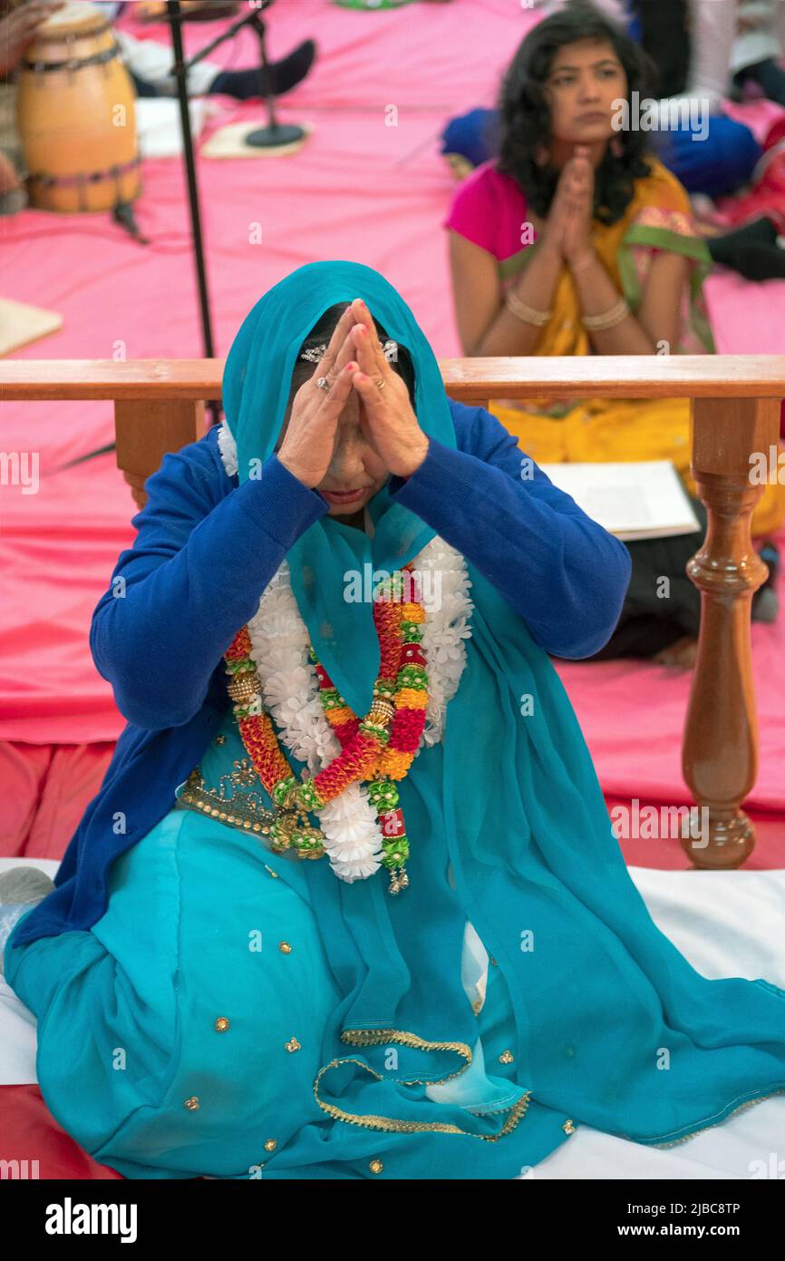 Eine hinduistische Gottesanbeterin kniet beim Gottesdienst zu ihrem Geburtstag. In Jamaika, Queens, New York City Stockfoto