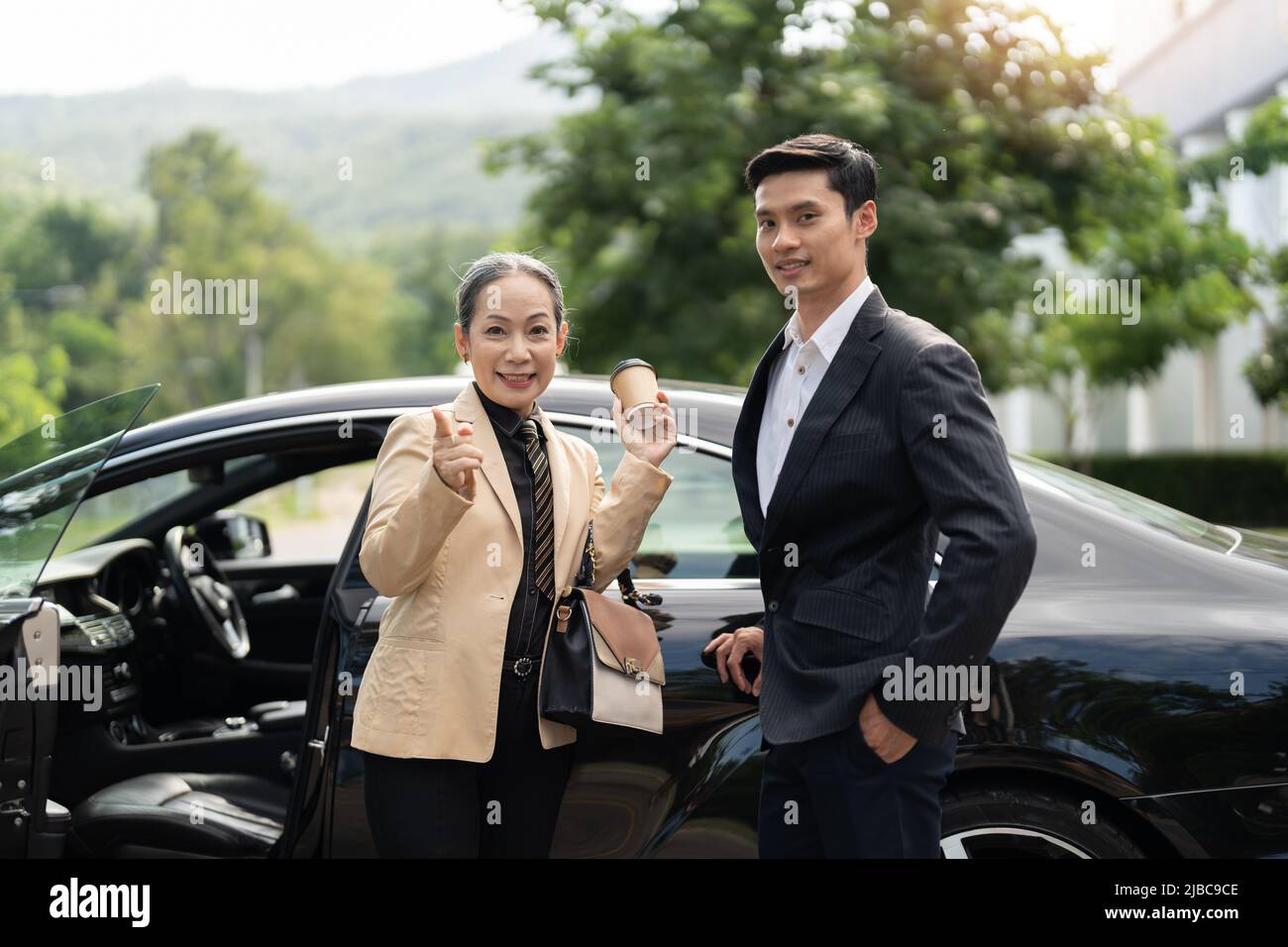 Glückliche alte asiatische Geschäftsfrau und junger asiatischer männlicher Kollege auf dem Parkplatz Stockfoto