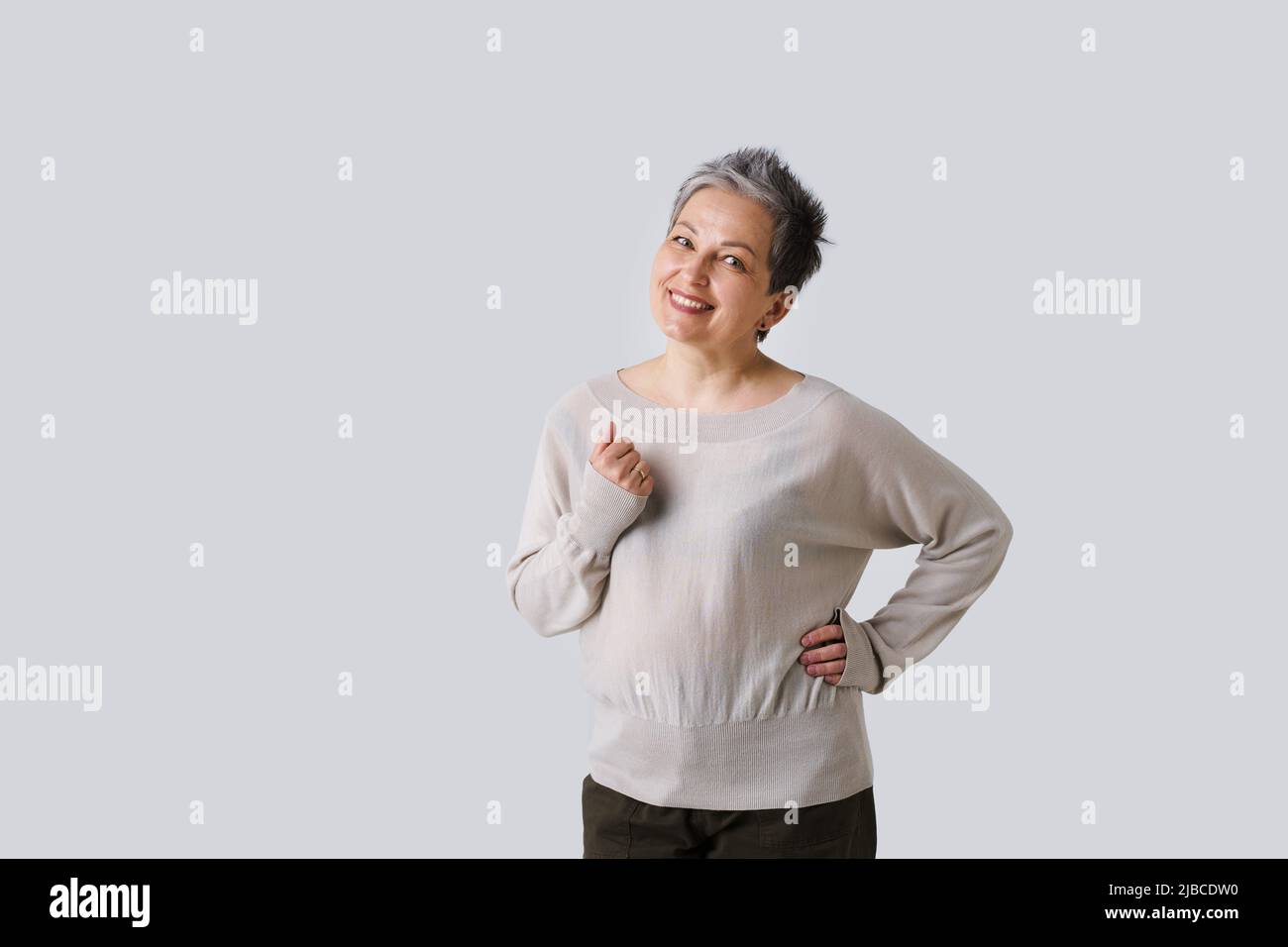 Zarte Mutter Look der reifen Frau mit grauen Haaren posiert mit Hand nach oben isoliert auf weißem Hintergrund. Platz und Platz für die Produktplatzierung kopieren. Getöntes Bild. Konzept der veralteten Schönheit. Stockfoto