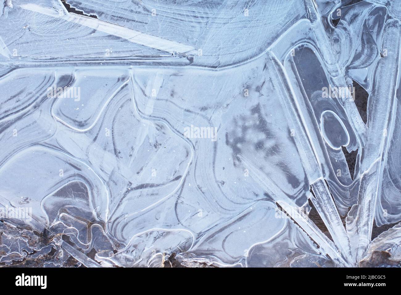 Eisiger Hintergrund, gefrorene Pfütze mit Eismustern, Nahaufnahme Stockfoto