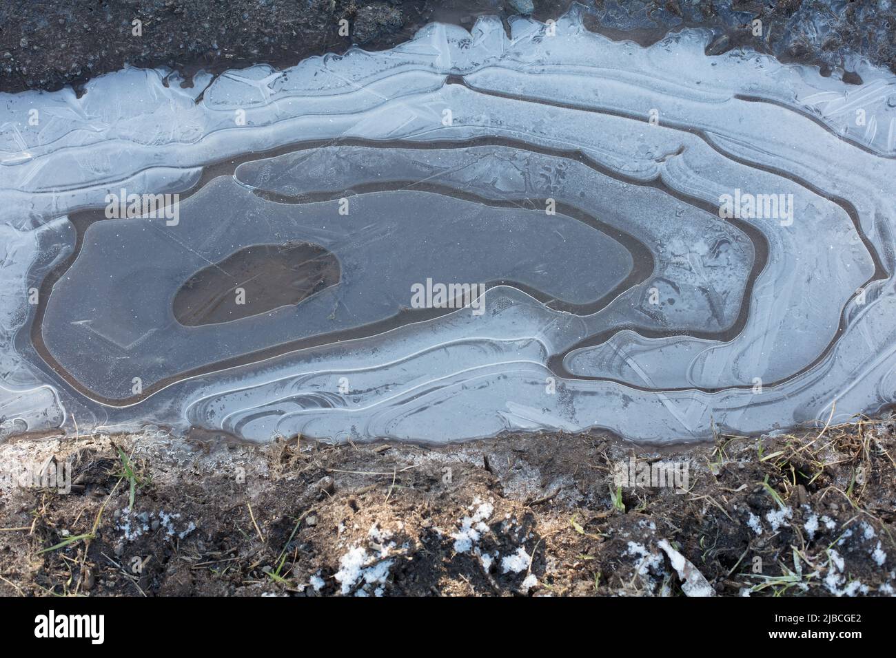 Natürliche Muster; kreisförmige Eismuster in gefrorenen Wasserpfützen im Winter Stockfoto
