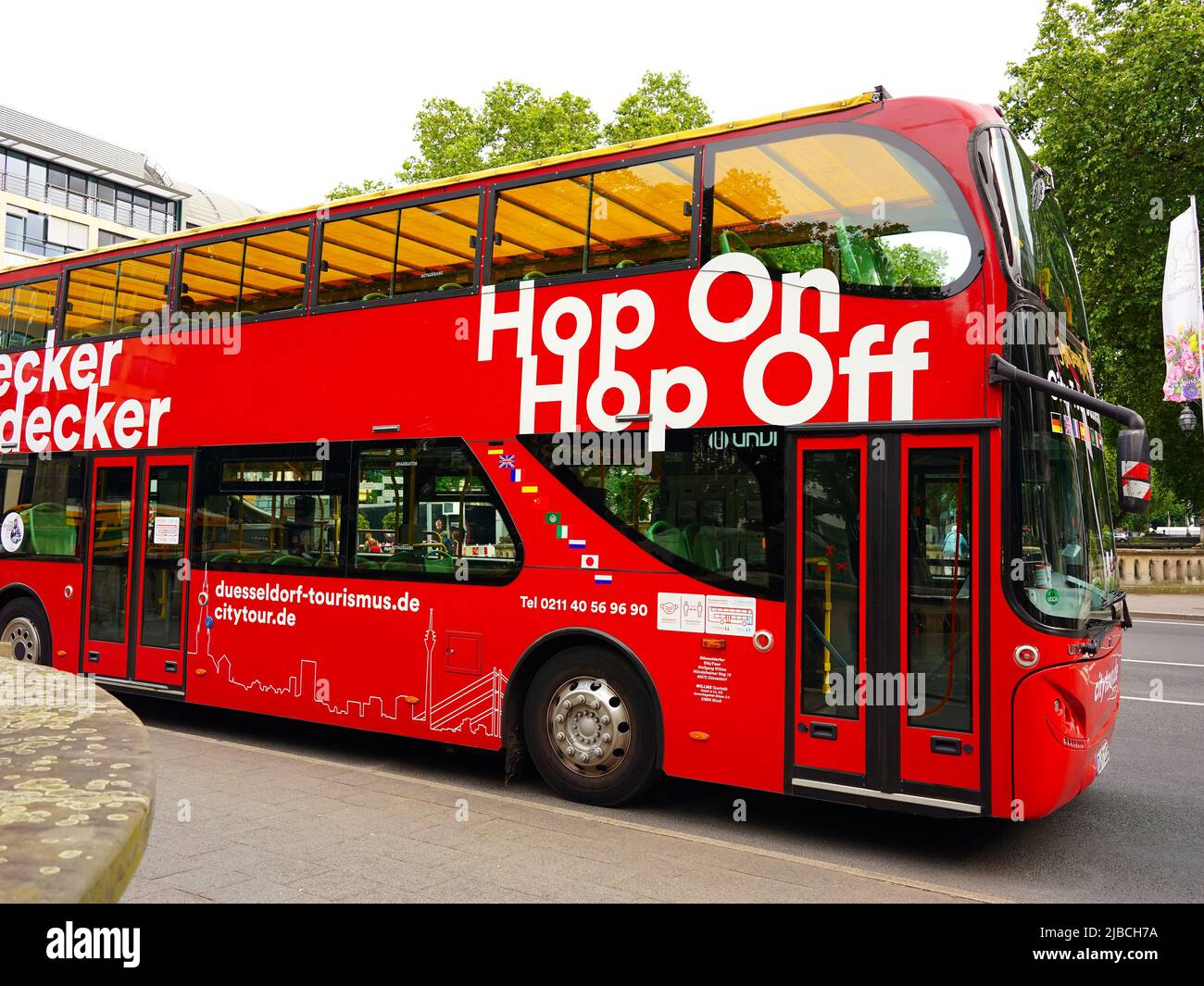 Rote Doppeldecker-Stadtrundfahrt 'Hop on / Hop off'-Bus, der an einer Haltestelle in der Königsallee in Düsseldorf/Deutschland wartet. Stockfoto