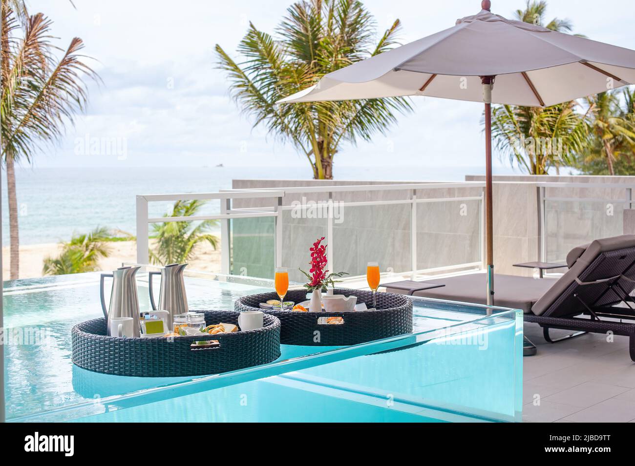 Schwimmende Tabletts mit Frühstück im Swimmingpool. Influencer oder Blogger genießen exotische Speisen im luxuriösen Spa des Hotels. Frische exotische Speisen mit Früchten. Luxus Stockfoto