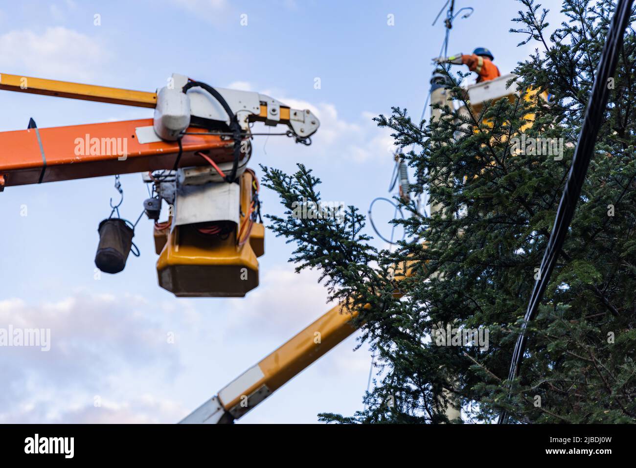 Ein Versorgungstechniker wird mit einem Kirschenpflücker-Lift bei der Arbeit gesehen, um nach starken Winden, die Bäume entwurzeln und Störungen verursachen, Zugang zu den Oberleitungen zu erhalten. Stockfoto