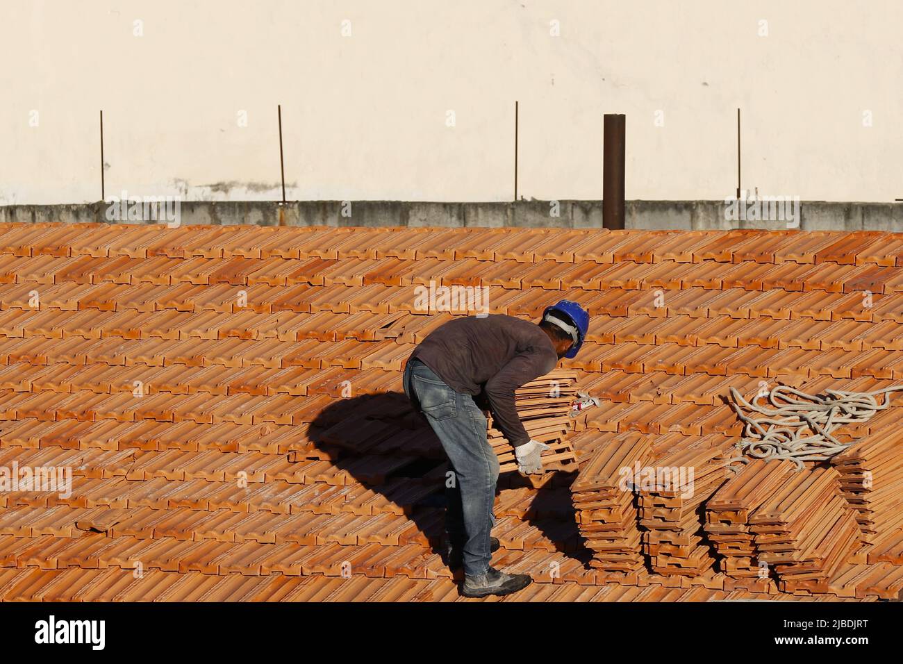 Dachdecker, der am Dachbau arbeitet. Reparatur des Ziegeldachs. Haus im Bau. Arbeiter renoviert Abdichtung Dach des Gebäudes. Zimmermann Stockfoto