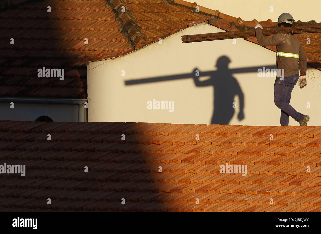 Dachdecker, der am Dachbau arbeitet. Reparatur des Ziegeldachs. Haus im Bau. Arbeiter renoviert Abdichtung Dach des Gebäudes. Zimmermann Stockfoto