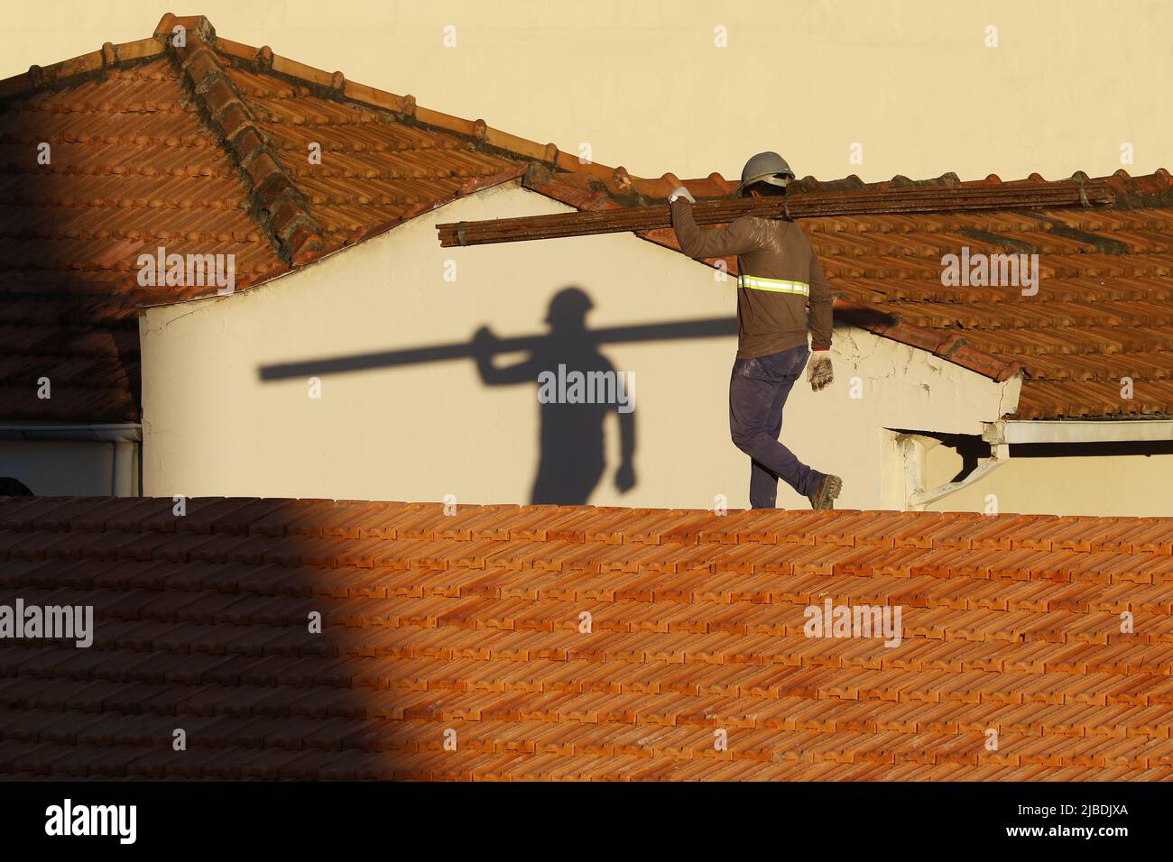 Dachdecker, der am Dachbau arbeitet. Reparatur des Ziegeldachs. Haus im Bau. Arbeiter renoviert Abdichtung Dach des Gebäudes. Zimmermann Stockfoto