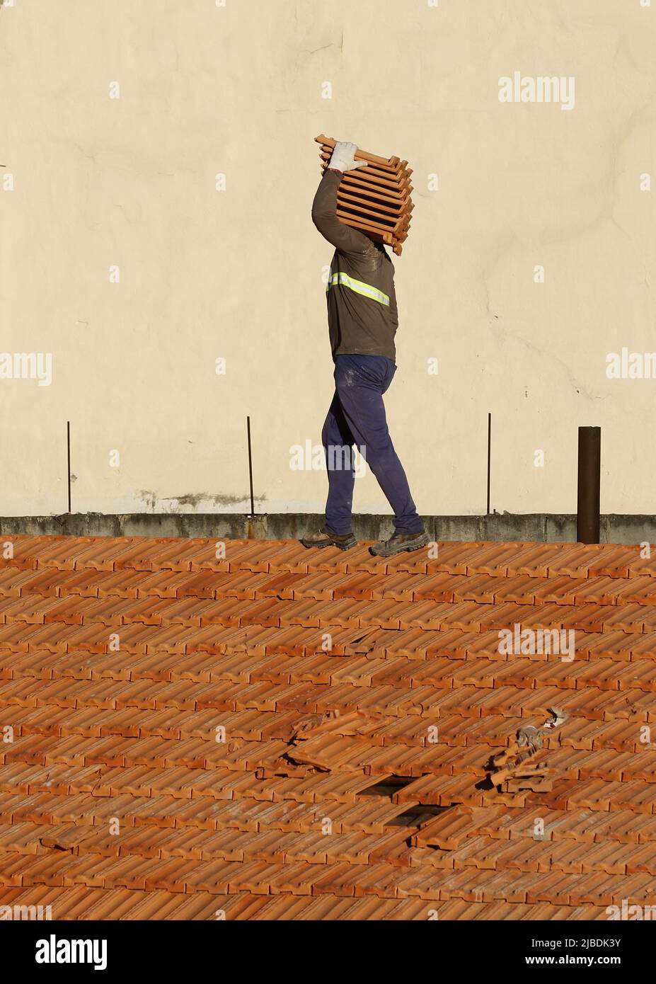 Dachdecker, der am Dachbau arbeitet. Reparatur des Ziegeldachs. Haus im Bau. Arbeiter renoviert Abdichtung Dach des Gebäudes. Zimmermann Stockfoto