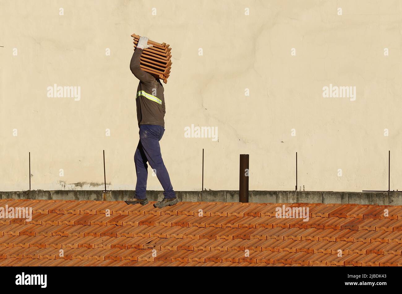 Dachdecker, der am Dachbau arbeitet. Reparatur des Ziegeldachs. Haus im Bau. Arbeiter renoviert Abdichtung Dach des Gebäudes. Zimmermann Stockfoto