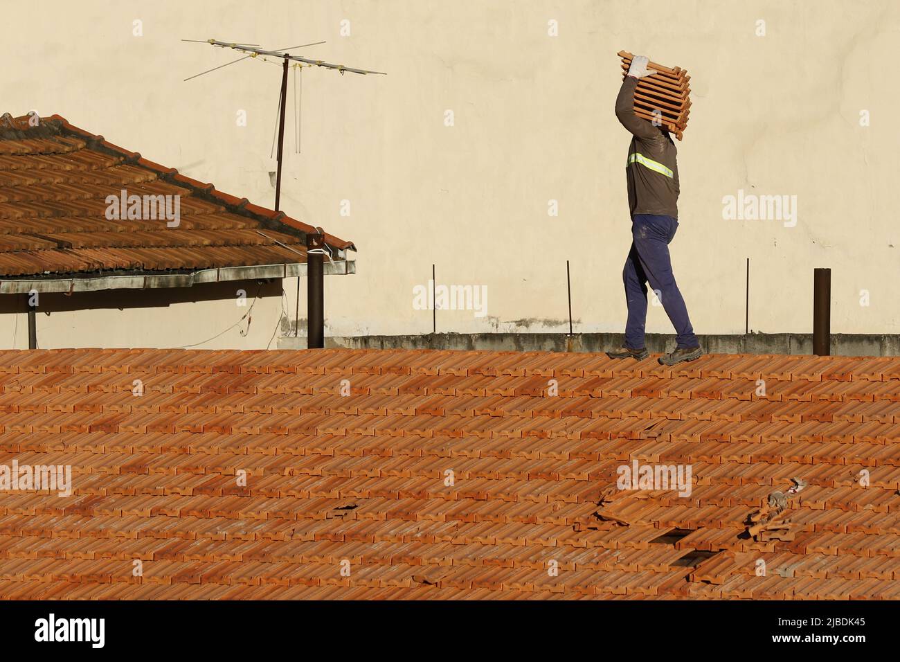 Dachdecker, der am Dachbau arbeitet. Reparatur des Ziegeldachs. Haus im Bau. Arbeiter renoviert Abdichtung Dach des Gebäudes. Zimmermann Stockfoto