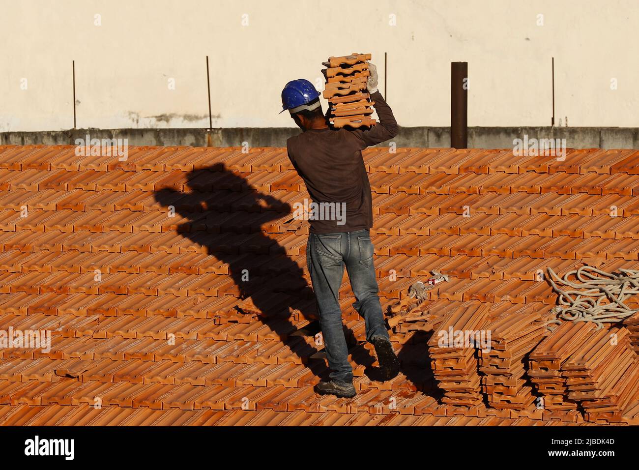 Dachdecker, der am Dachbau arbeitet. Reparatur des Ziegeldachs. Haus im Bau. Arbeiter renoviert Abdichtung Dach des Gebäudes. Zimmermann Stockfoto