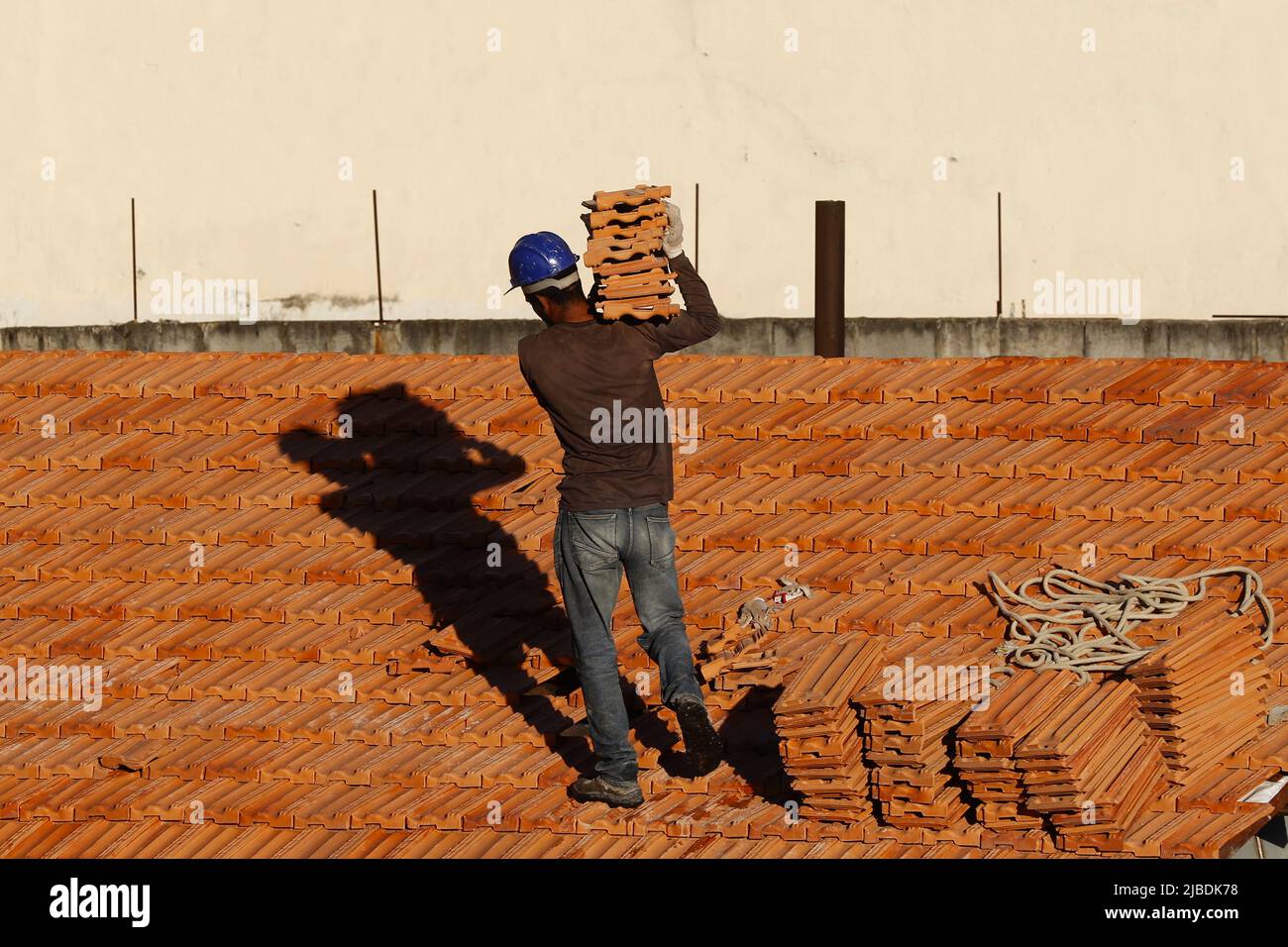 Dachdecker, der am Dachbau arbeitet. Reparatur des Ziegeldachs. Haus im Bau. Arbeiter renoviert Abdichtung Dach des Gebäudes. Zimmermann Stockfoto