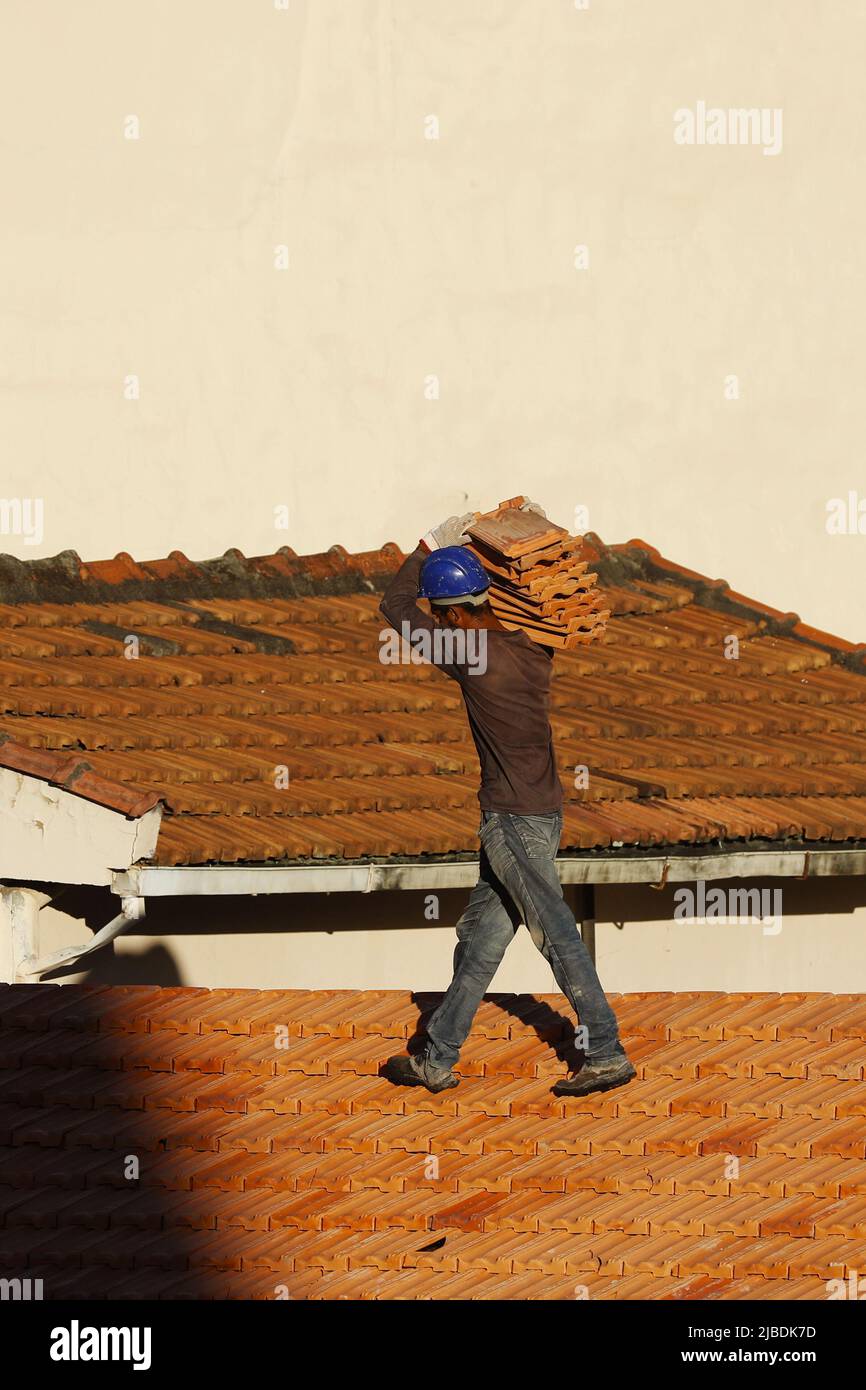 Dachdecker, der am Dachbau arbeitet. Reparatur des Ziegeldachs. Haus im Bau. Arbeiter renoviert Abdichtung Dach des Gebäudes. Zimmermann Stockfoto