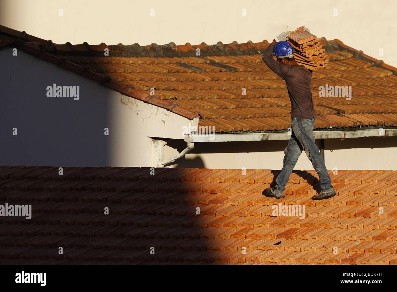 Dachdecker, der am Dachbau arbeitet. Reparatur des Ziegeldachs. Haus im Bau. Arbeiter renoviert Abdichtung Dach des Gebäudes. Zimmermann Stockfoto