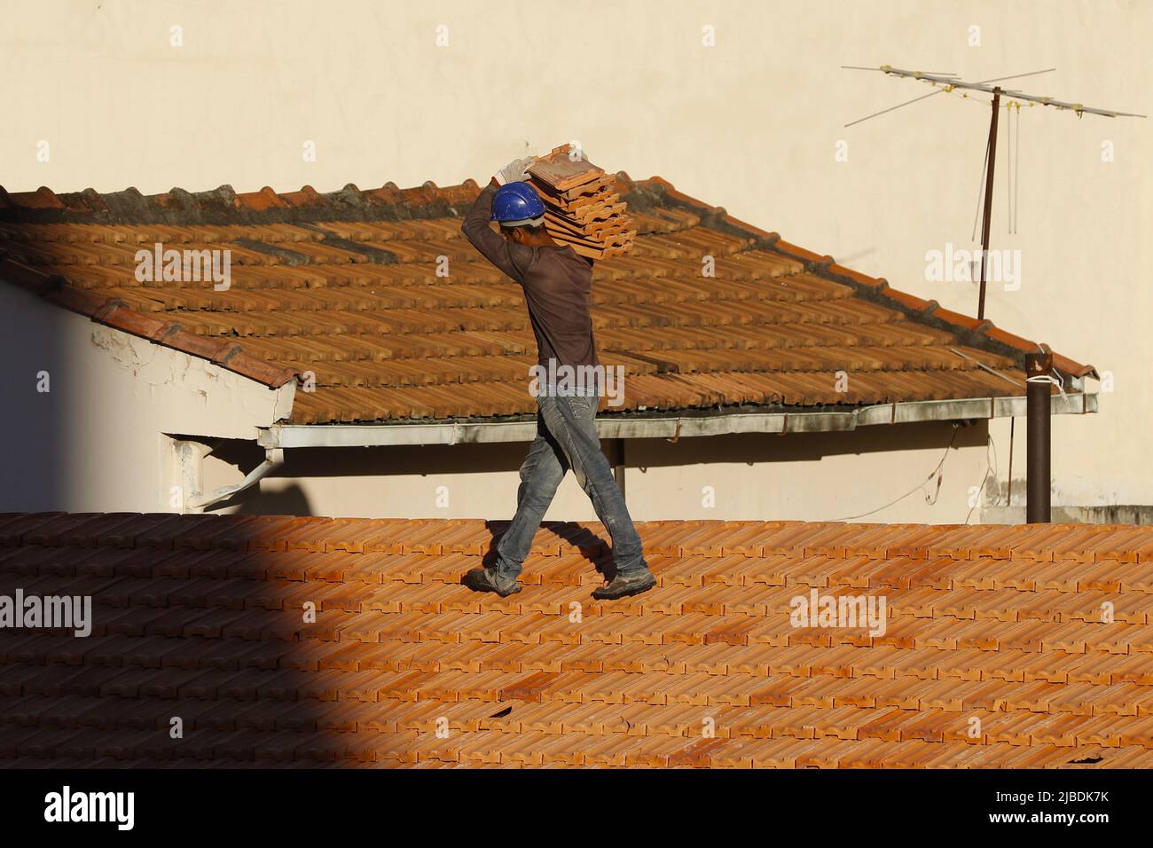 Dachdecker, der am Dachbau arbeitet. Reparatur des Ziegeldachs. Haus im Bau. Arbeiter renoviert Abdichtung Dach des Gebäudes. Zimmermann Stockfoto