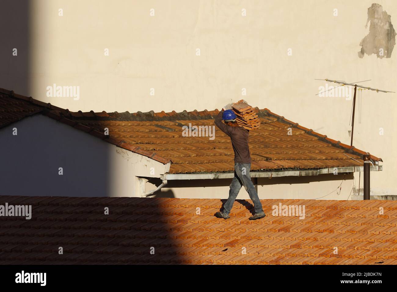 Dachdecker, der am Dachbau arbeitet. Reparatur des Ziegeldachs. Haus im Bau. Arbeiter renoviert Abdichtung Dach des Gebäudes. Zimmermann Stockfoto