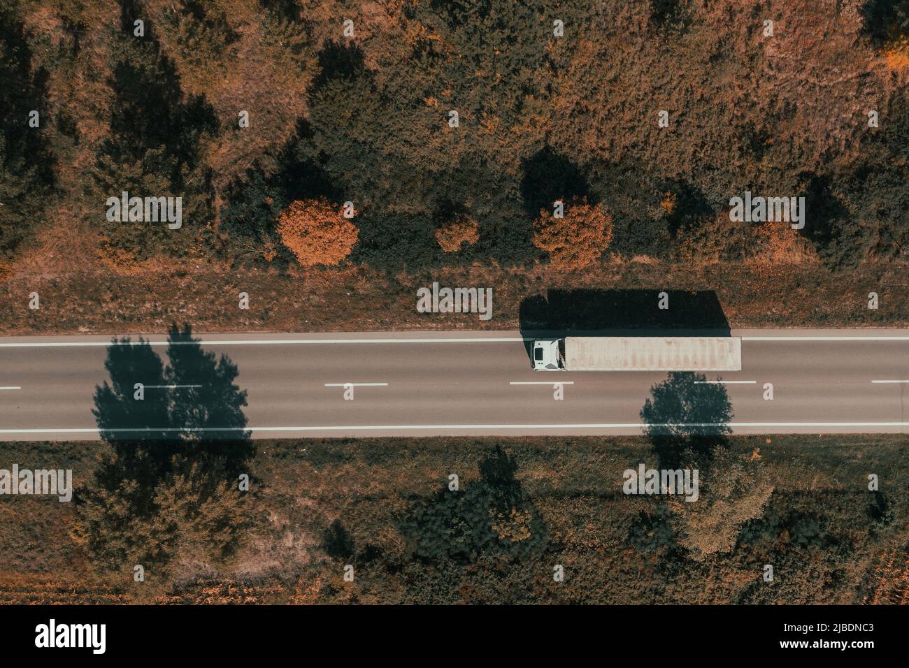 Luftaufnahme eines Gütertransportwagens auf der Straße am Sommernachmittag, Drone-Bild von oben nach unten vom Fahrzeug, das die Straße entlang fährt Stockfoto