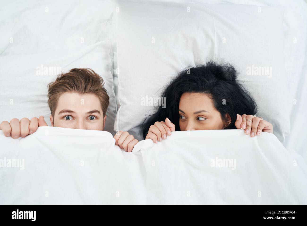 Weibchen und Männchen verstecken ihre Gesichter hinter einer Decke Stockfoto
