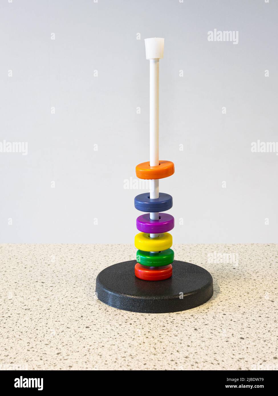 Farbige Magnetringe um einen Stab schweben aufgrund der abstoßenden magnetischen Kraft übereinander. Experimentieren Sie im Physikunterricht. Stockfoto