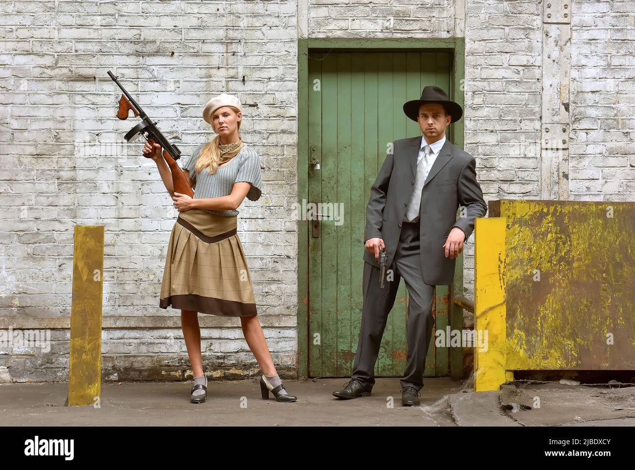 Ein junges Paar verkleidet sich in Vintage-Kleidung im 1930-Stil. Sie tragen jeweils eine Waffe, während sie die Rolle des berühmten Gangsterduos Bonnie und Clyde übernehmen. Stockfoto