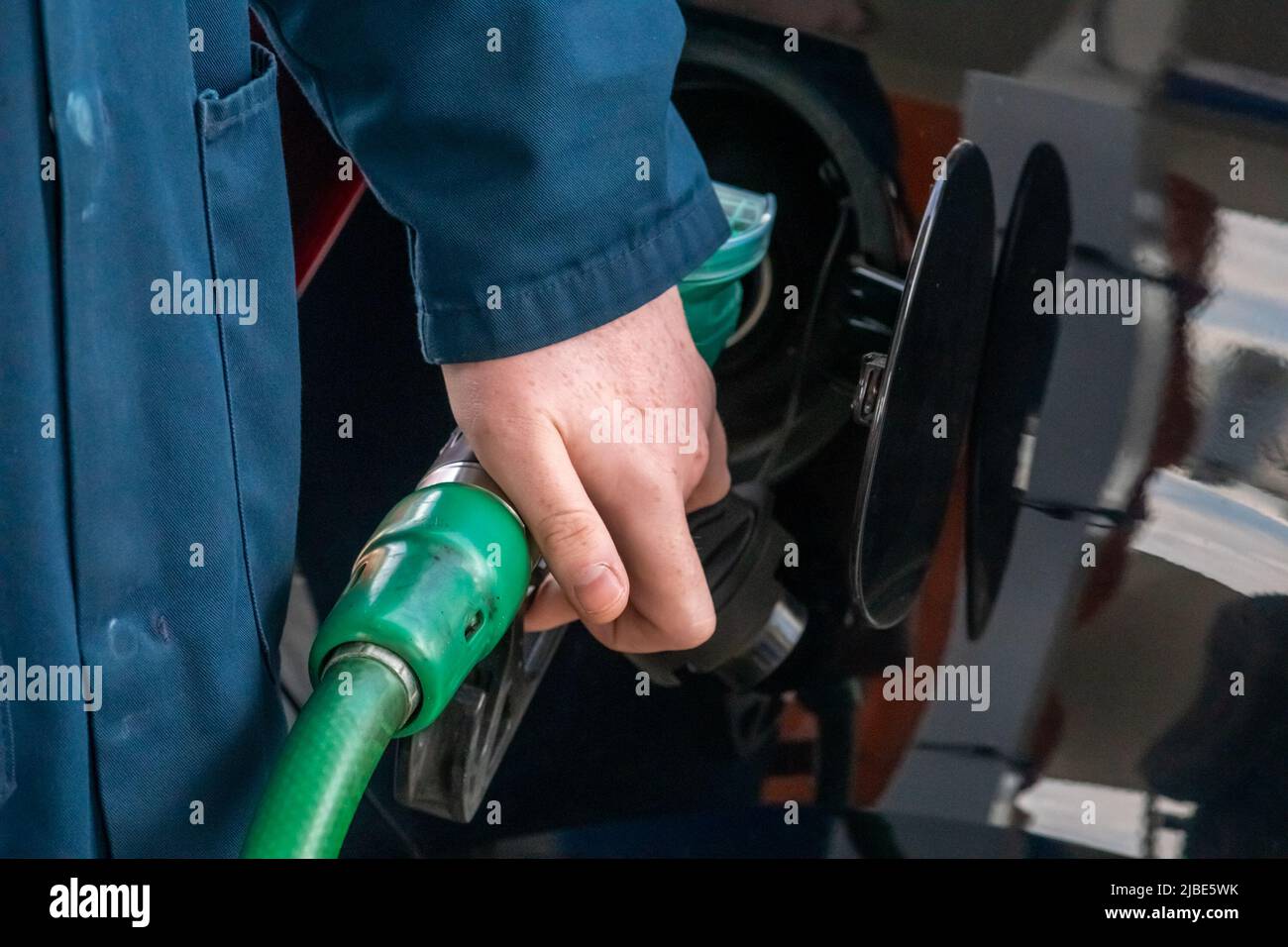 Tankstellenwärter, der bleifreies Benzin in ein Auto auf dem Vorplatz abgibt. Ansicht schließen. In Großbritannien ist der Service der Aufsichtsperson heutzutage selten Stockfoto