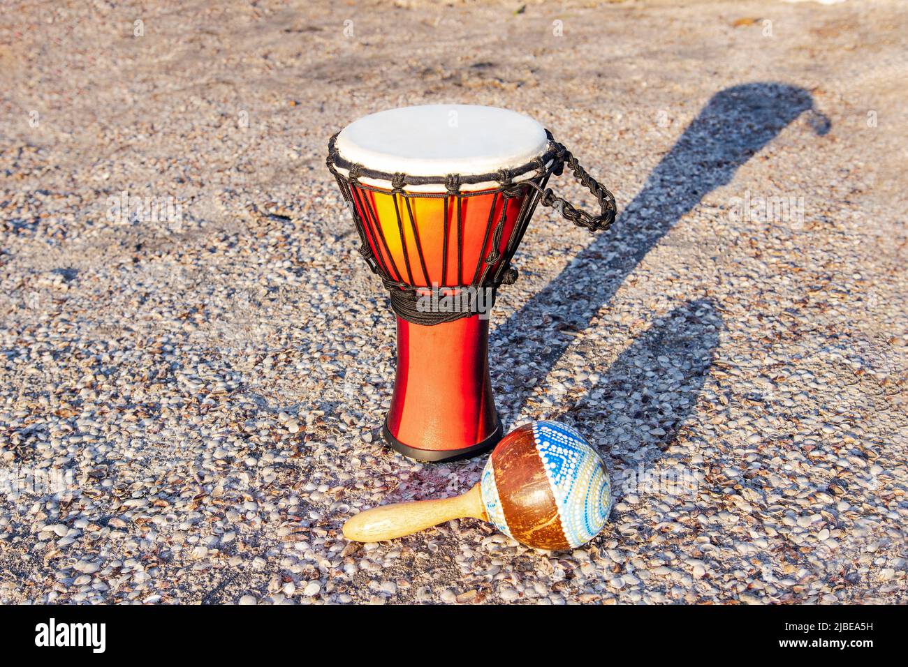 Afrikanisches Schlaginstrument Djembe und Marokas auf dem Sand in der Nähe des Ozeans. National African and Latin American Exotic Percussion Instruments at the Stockfoto