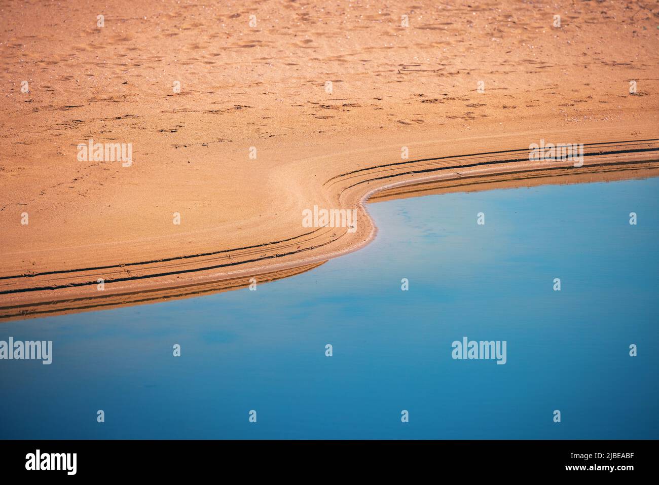 Oase in einer Wüste. Sand und Wasser, Abdrücke von Wellen. Stockfoto