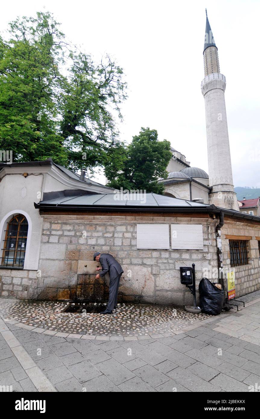 Ein bosnischer Mann trinkt Wasser aus dem Trinkbrunnen der Gazi-Husrev-Beg-Moschee Stockfoto