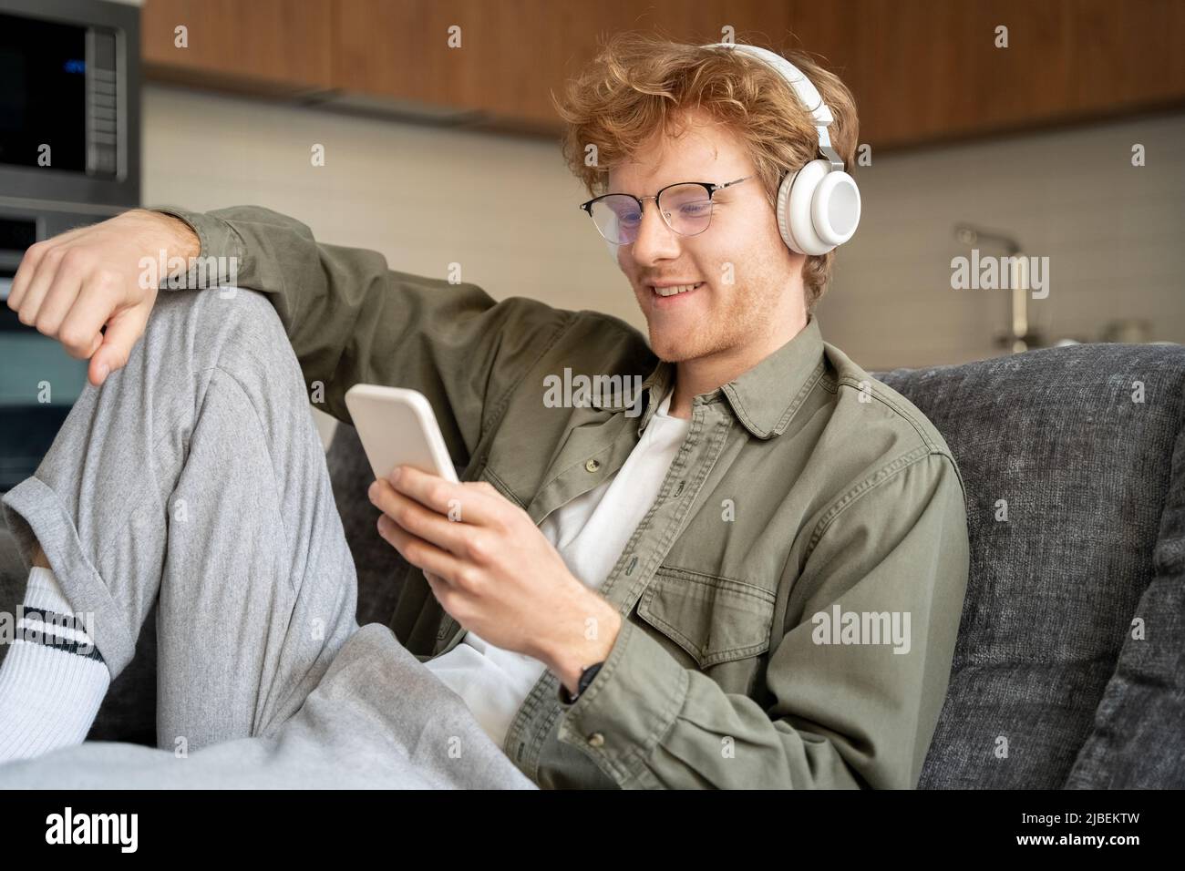Junger britischer Ingwer im Headset, der Videoanruf mit dem Mobiltelefon führt Stockfoto