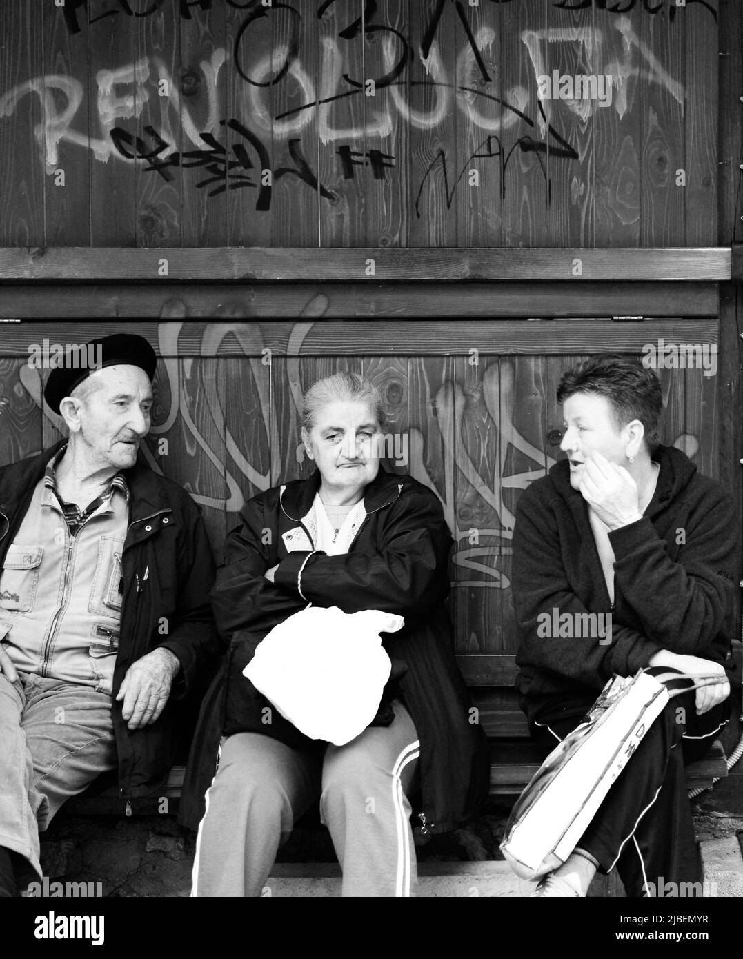 Ältere Bosnier, die unter einem Graffiti der Revolution in Sarajevo, Bosnien und Herzegowina sitzen. Stockfoto