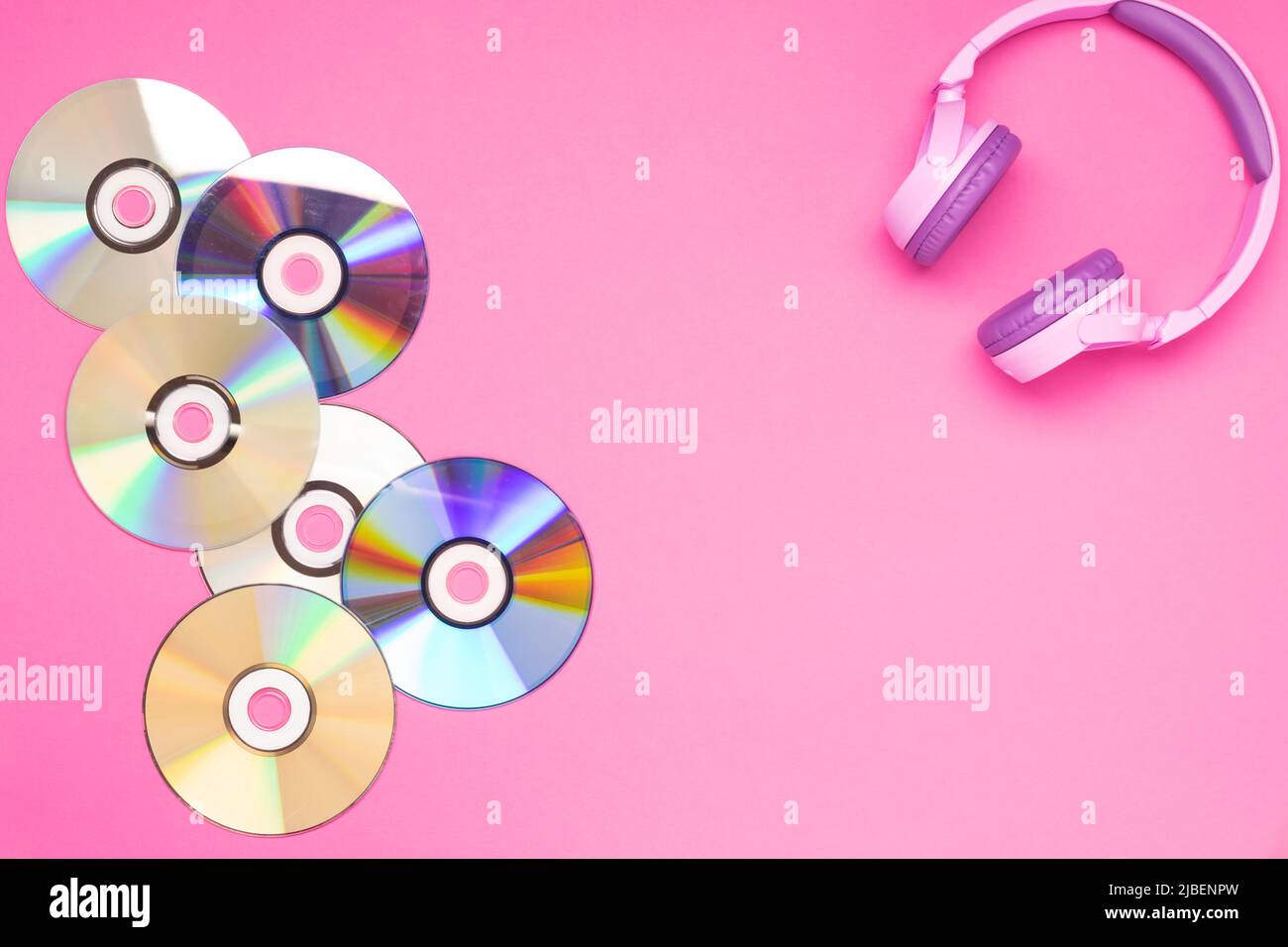 Pinke Jugendkopfhörer Musik-cd-Discs auf einem rosa Hintergrund, flacher Lay-Copy-Platz. Hobby-Entertainment-Technologie Stockfoto