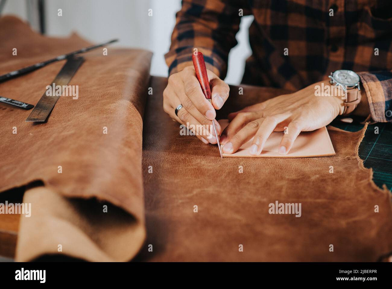 Der Mann, der in der Werkstatt mit echtem Leder arbeitet. Stockfoto