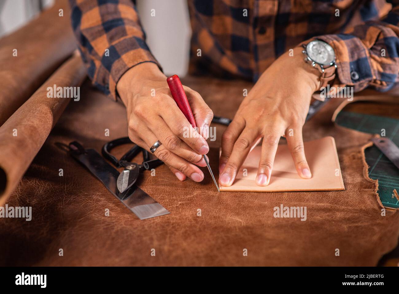 Der Mann, der in der Werkstatt mit echtem Leder arbeitet. Stockfoto