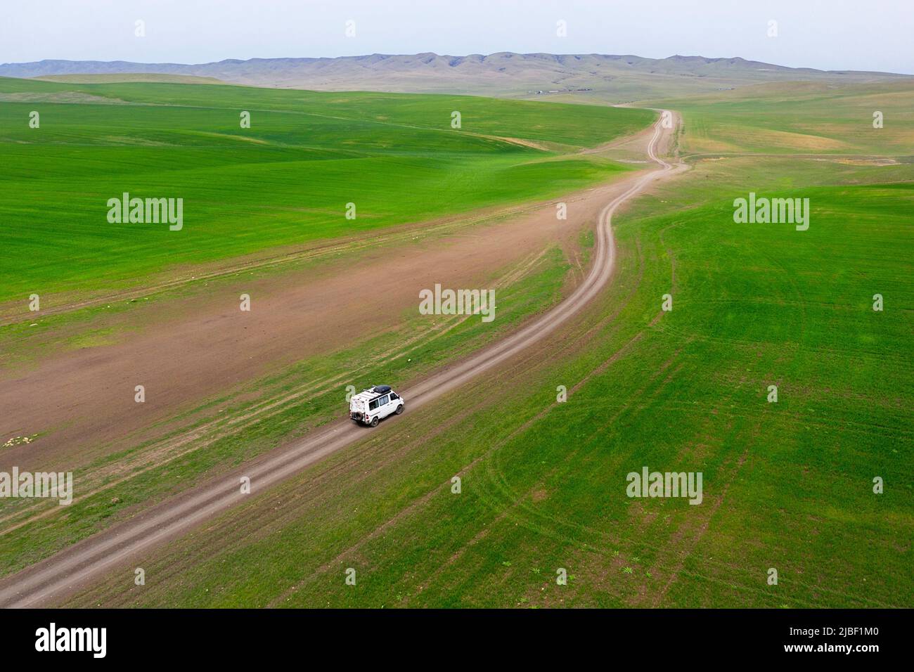 Tourist in einem 4x4-Wohnmobil auf einer windigen Straße, die wunderschöne grasbedeckte Ebenen überquert und zum Vashlovani-Nationalpark, Georgia, führt Stockfoto