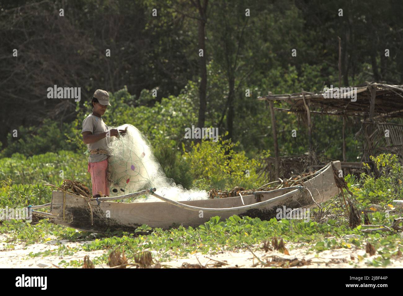 Ein Subsistenzfischer, der sein Fischernetz am Strand von Tarimbang in Tabung, East Sumba, East Nusa Tenggara, Indonesien, abrollt. Stockfoto