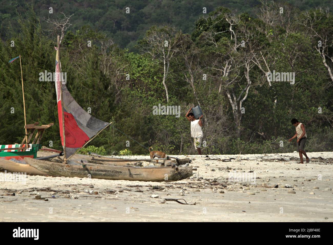 Ein Fischer, der eine jerry-Dose trägt, während er auf Holzkanus am Tarimbang-Strand in Tabung, East Sumba, East Nusa Tenggara, Indonesien, zuläuft. Stockfoto