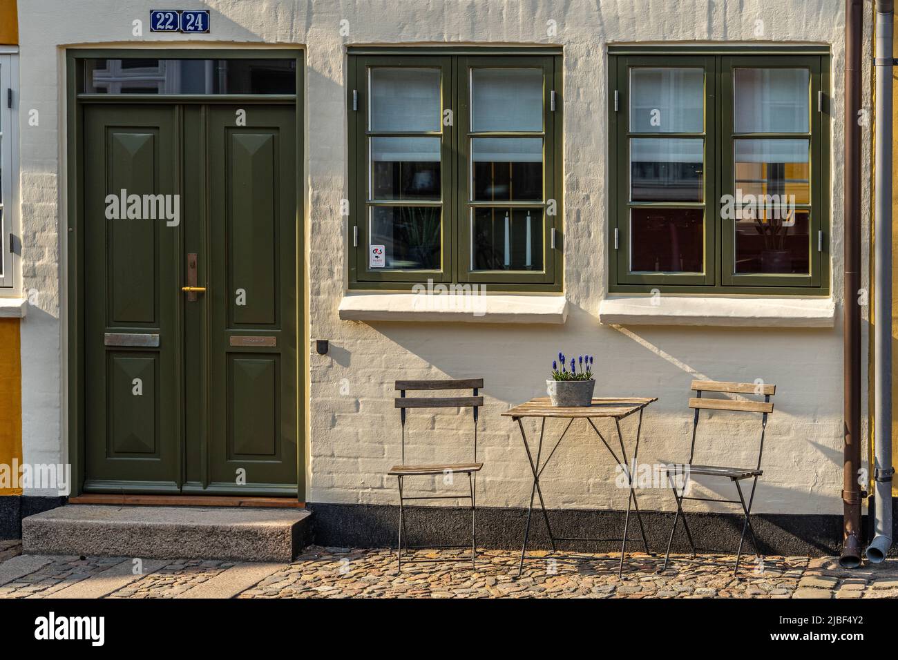 Charakteristisches dänisches Haus mit einem kleinen Raum, um die Frühlingssonne mit zwei Stühlen und einem Tisch zu genießen. Odense, Fyn, Dänemark, Europa Stockfoto