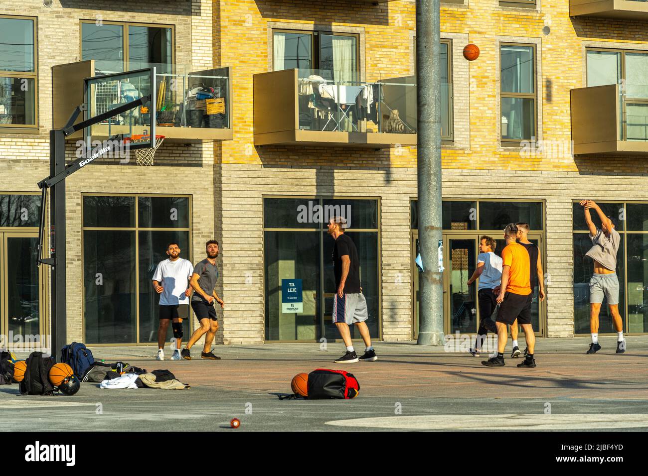 Eine Gruppe junger Leute spielt Basketball auf der Straße in der Nähe des Yachthafens. Odense, Fünen Island, Dänemark, Europa Stockfoto