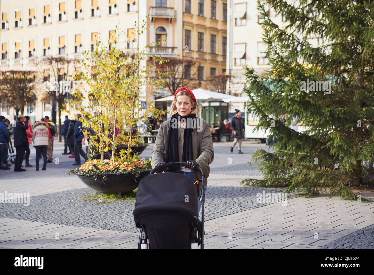 Frau mit Kinderwagen auf der Stadtstraße Stockfoto