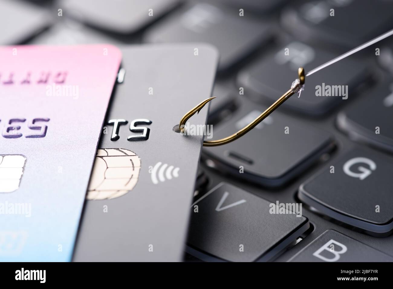 Kreditkarte auf Angelhaken aus dem Stapel auf der Tastatur gezogen, Phishing-Betrug Datendiebstahl Konzept Stockfoto