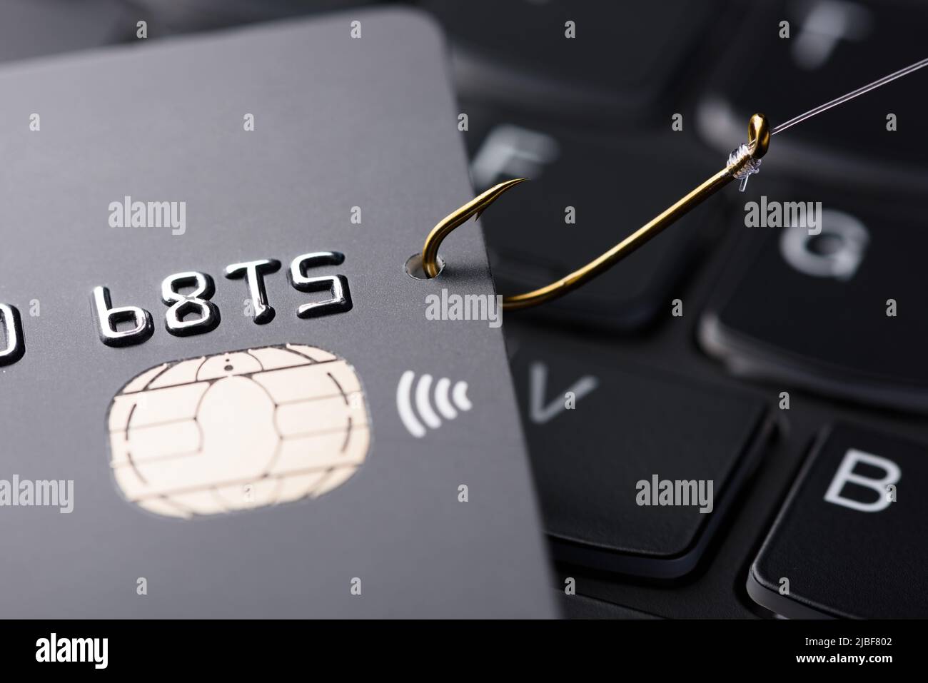 Konzept für Phishing-Betrug mit Kreditkarte. Kreditkartendatendiebstahl, Karte von Hacker-Cyber-kriminellen auf Angelhaken auf der Tastatur gehakt. Stockfoto