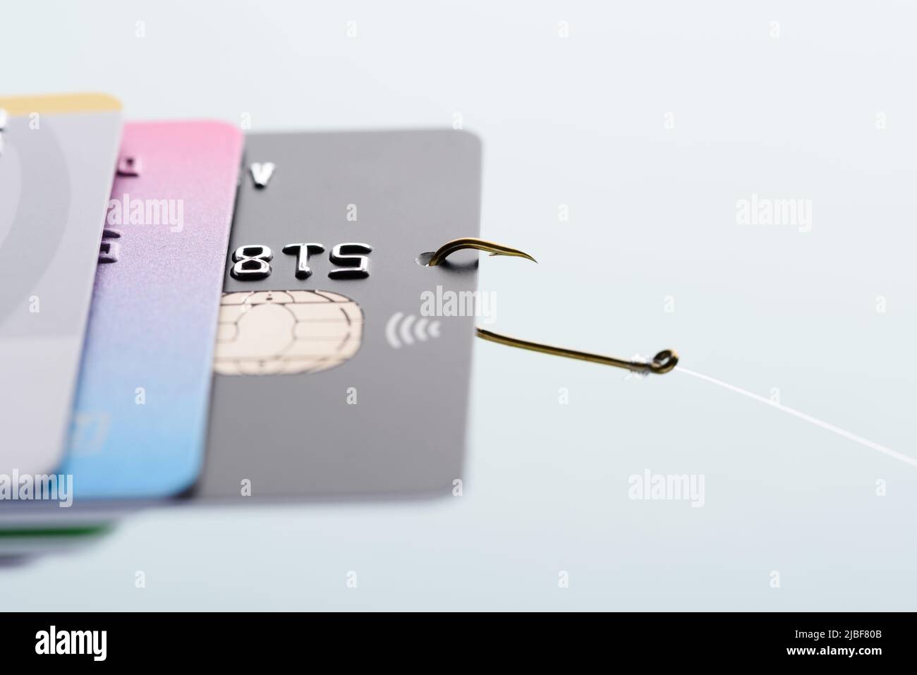 Konzept für Phishing-Betrug mit Kreditkarte. Diebstahl von Kreditkartendaten, Karte am Angelhaken aus dem Stapel gezogen. Stockfoto