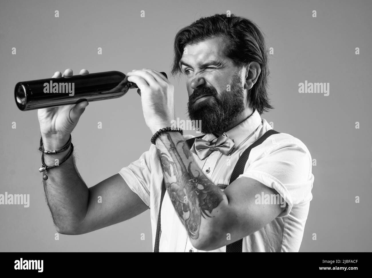 Auf der Suche nach dem letzten Tropfen. Brutaler Barkeeper in Fliege. Eleganter Barkeeper. Hübscher Hipster, der Weinglas trinkt. Sommelier, der Alkohol schmeckte Stockfoto